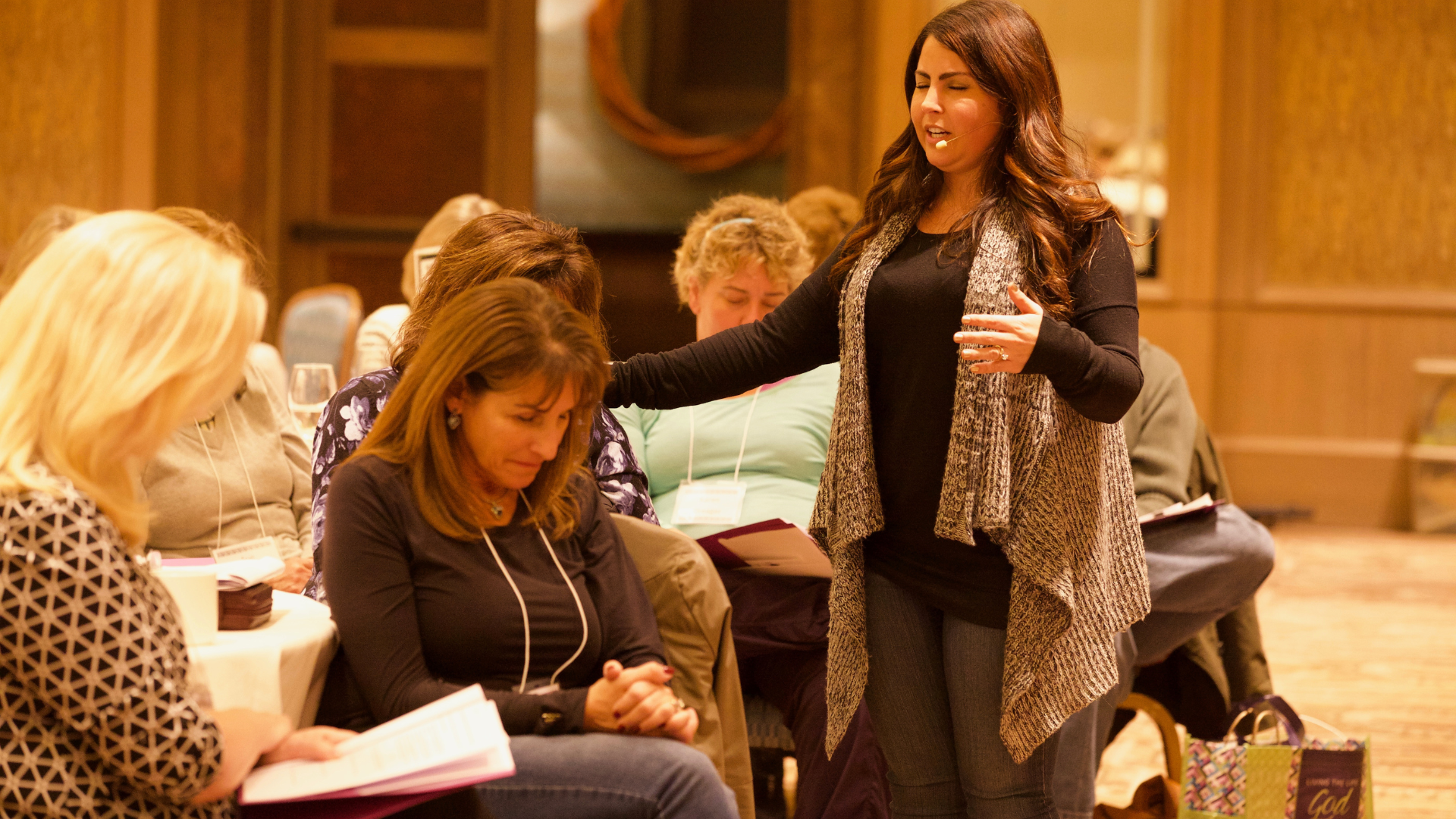 kari speaking at event praying for a woman with brown hair woman